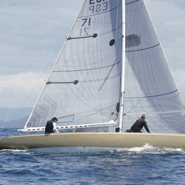 Six Metre sailing boat with beige hull and white sails.