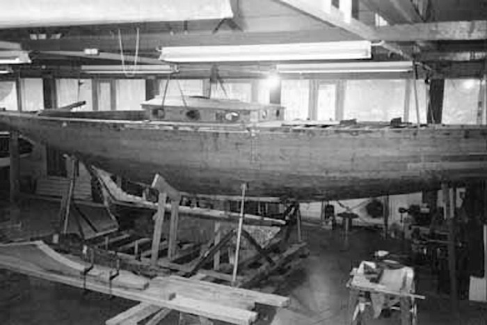 the hull of a yacht with a cabin top on a support in a workshop