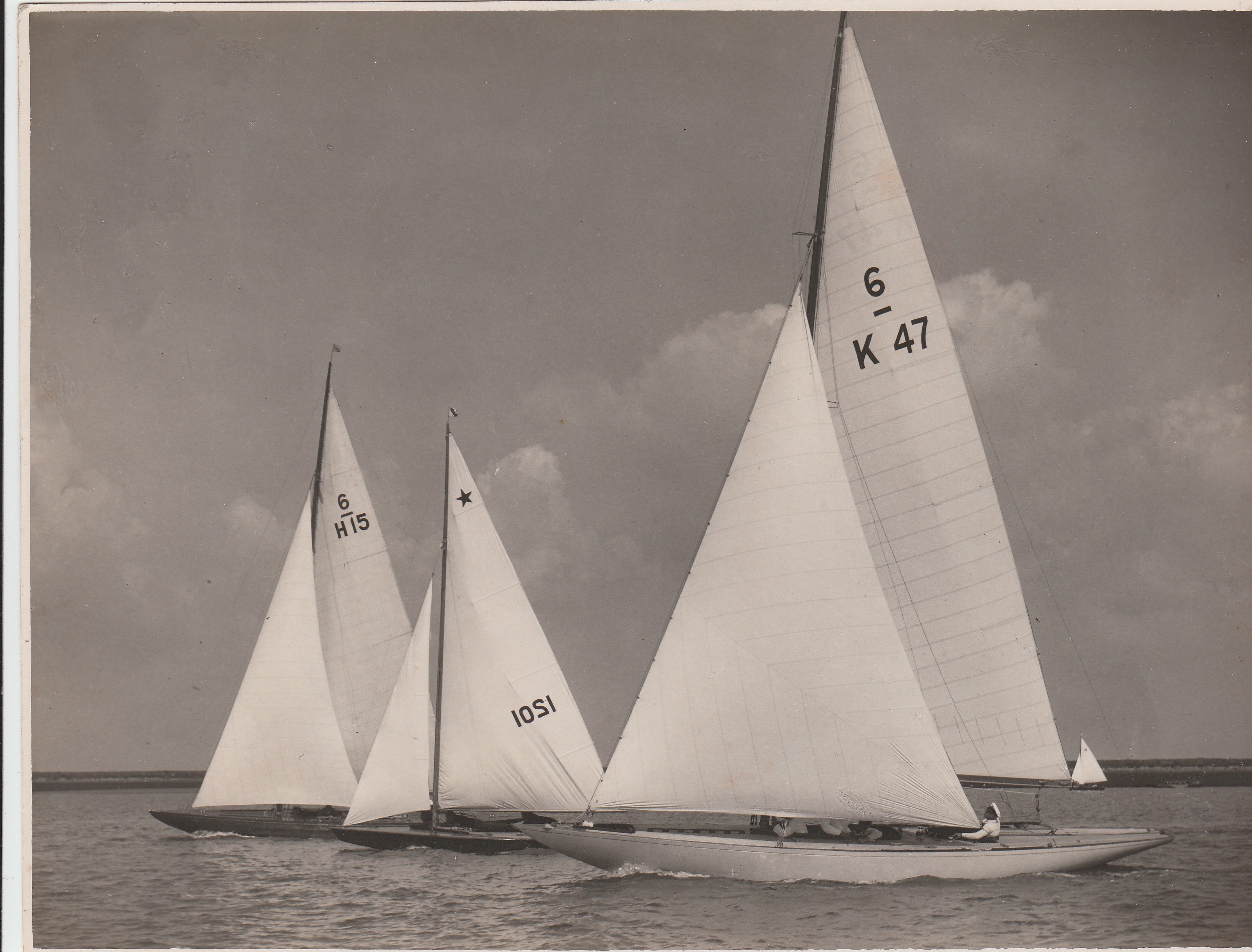 Black and white photograph of three sailing boats. The boat in the centre is a Star Class and the two either side are Six Metres.