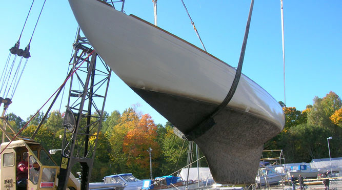 A colour photo of a wooden yacht on a hoist