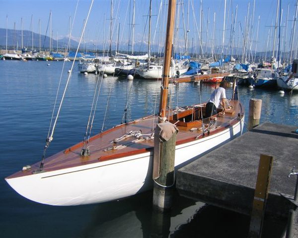 A colour photo of a wooden yacht moored in blue water