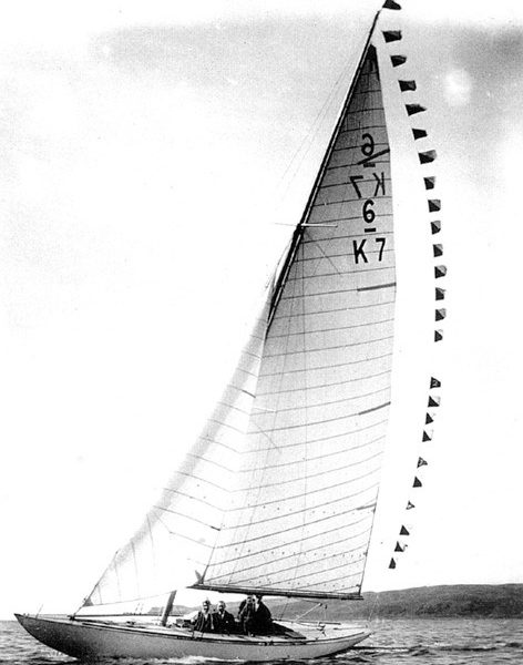 Black and white photo of a yacht with a white sail sailing.