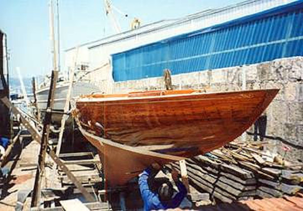 Polished wooden hull with a red painted keel.