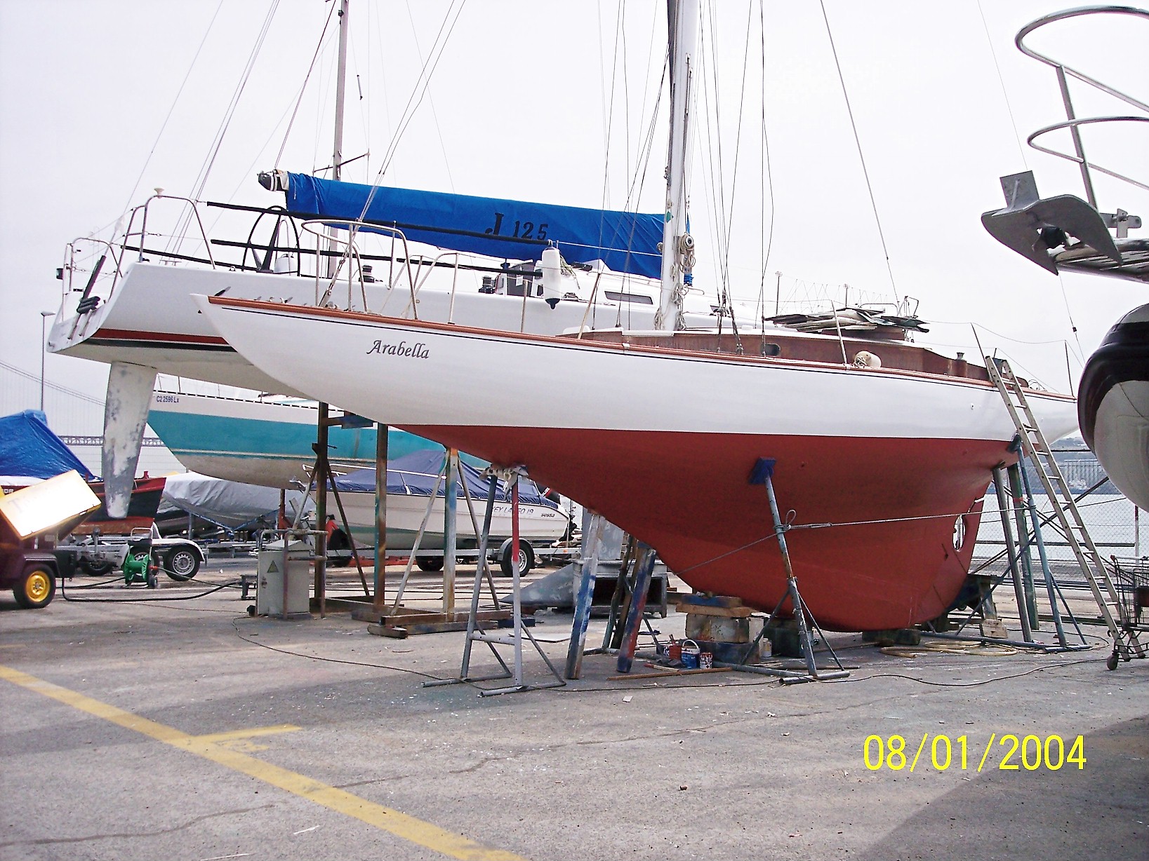 A white yacht with a red keel, on the hard.